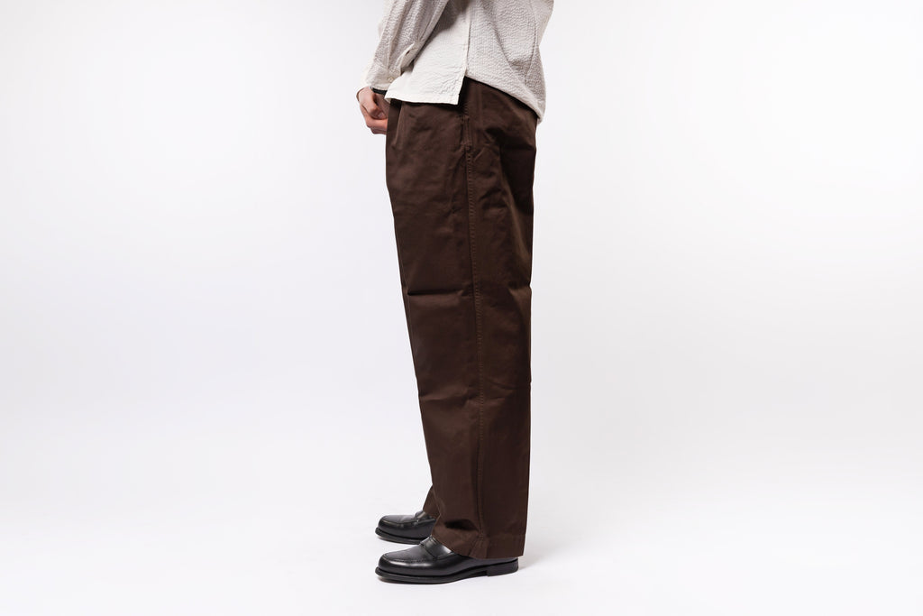 Person wearing brown pants and a light-colored shirt on a white background