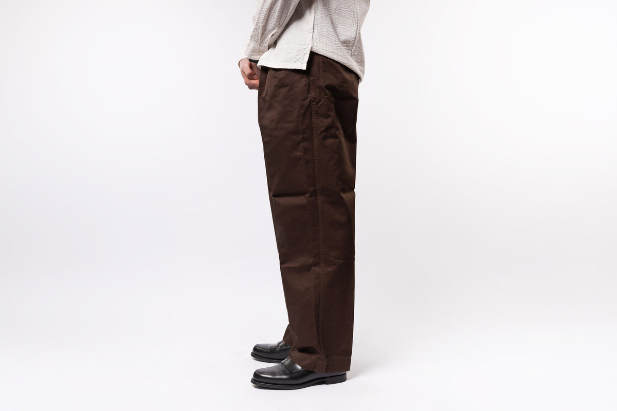Person wearing brown pants and a light-colored shirt on a white background