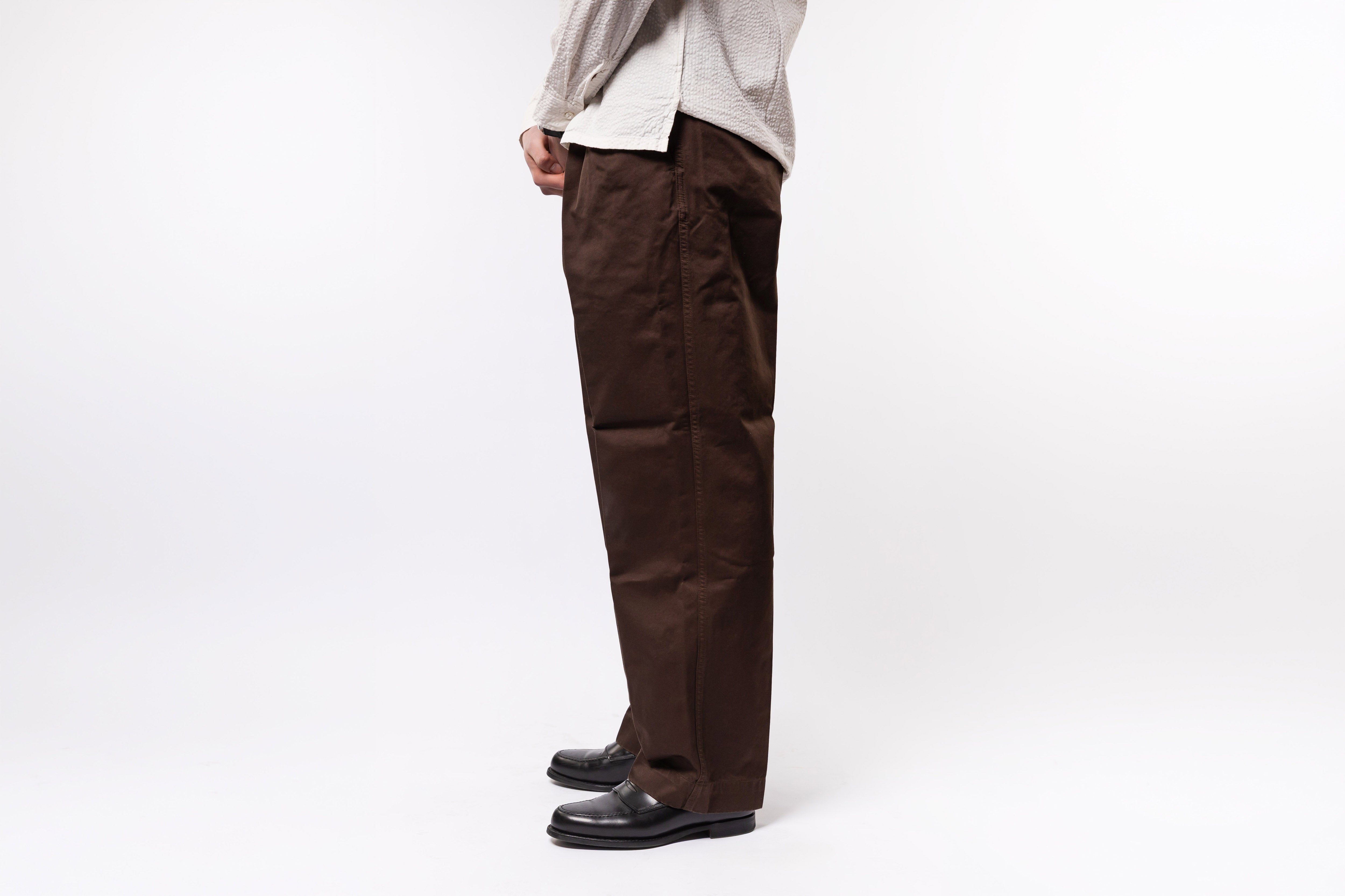 Person wearing brown pants and a light-colored shirt on a white background