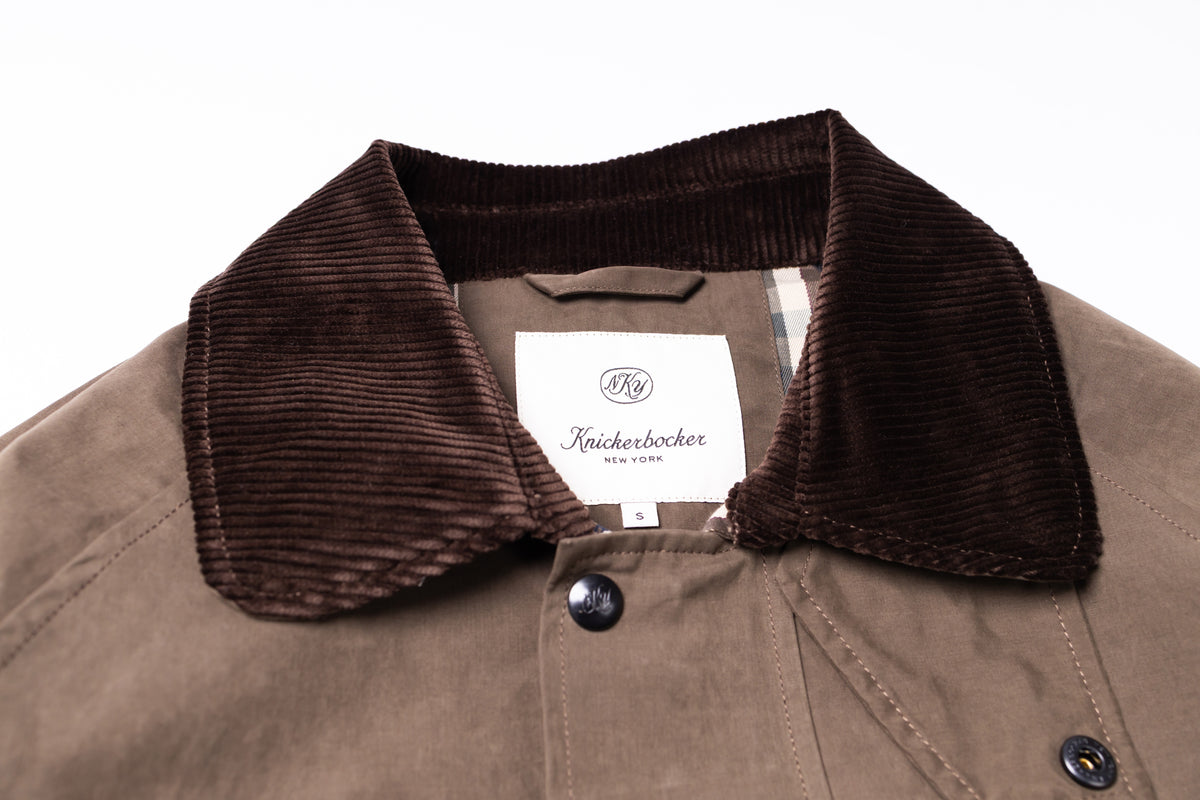 Close-up of a brown corduroy collar and brown jacket body with a white Keikerbocker neck label on a white background.