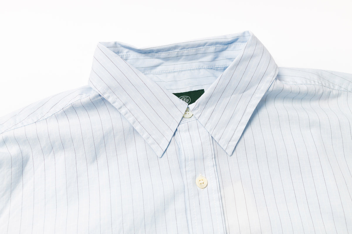 Close-up of a light blue striped shirt with a collar and button on a white background