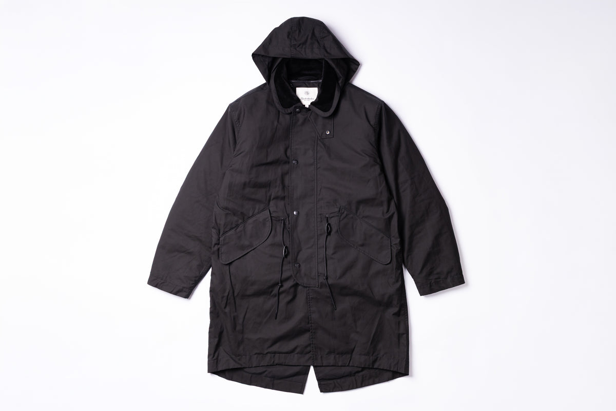 A black hooded utility jacket with front flap pockets, laid flat against a clean white background.