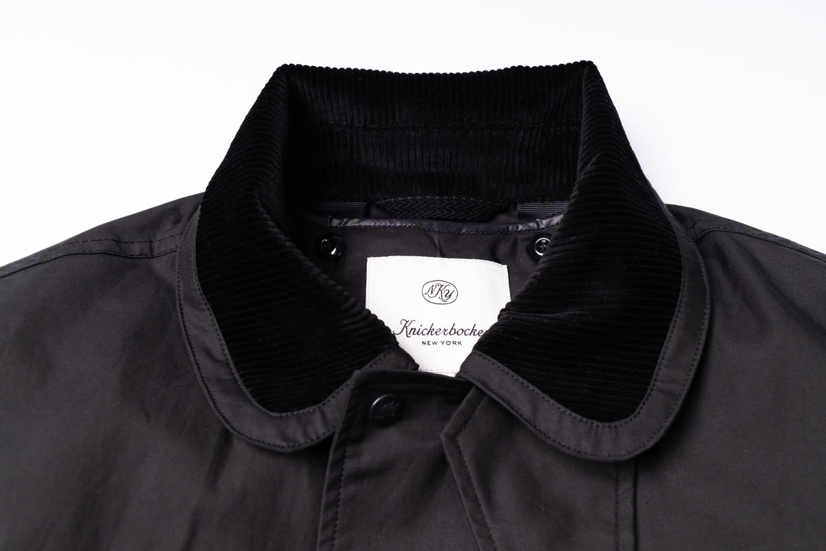 Close-up of a black jacket collar featuring a contrasting black corduroy inner collar and a white interior label reading 'Knick Knick New York'.