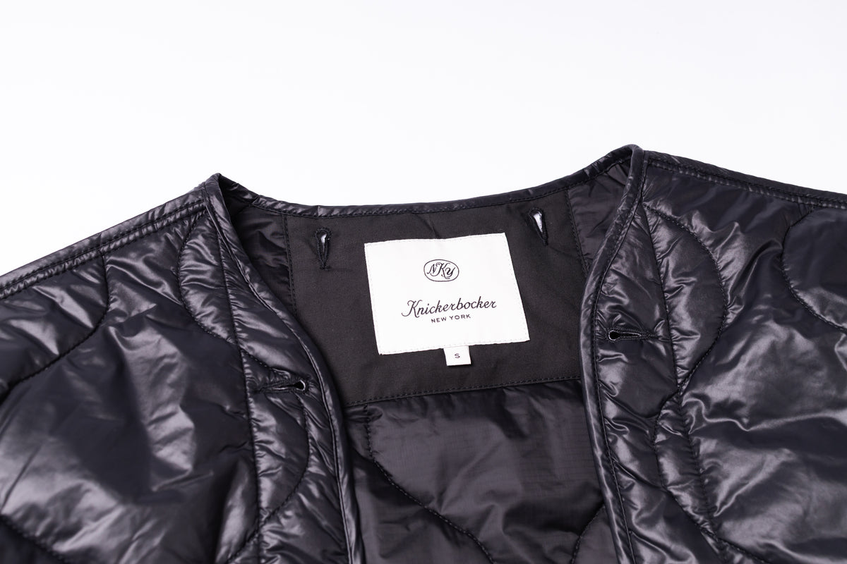 Close-up of a black quilted jacket showing the interior collar with a white label that reads 'Knickerbocker New York'.