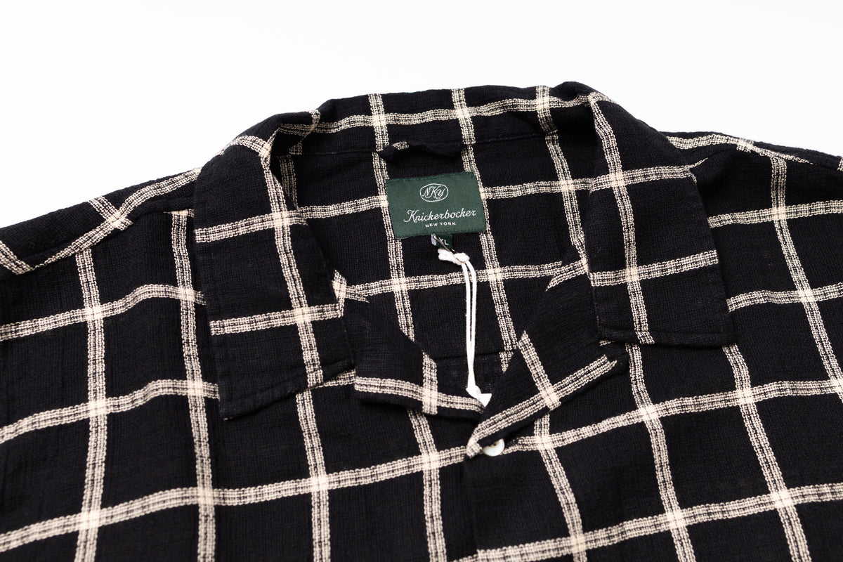 Black and white checkered shirt with a brand tag on a white background