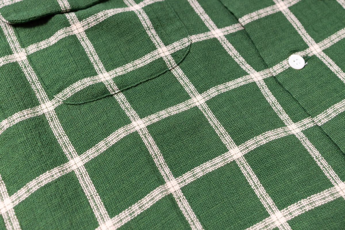 Close-up of a green checkered shirt with white lines on a green background