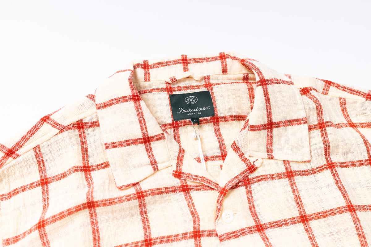 Red and white checkered shirt with a brand label on a light gray background