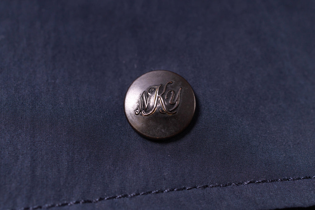 Close-up of a button with 'NKY' on a dark fabric background
