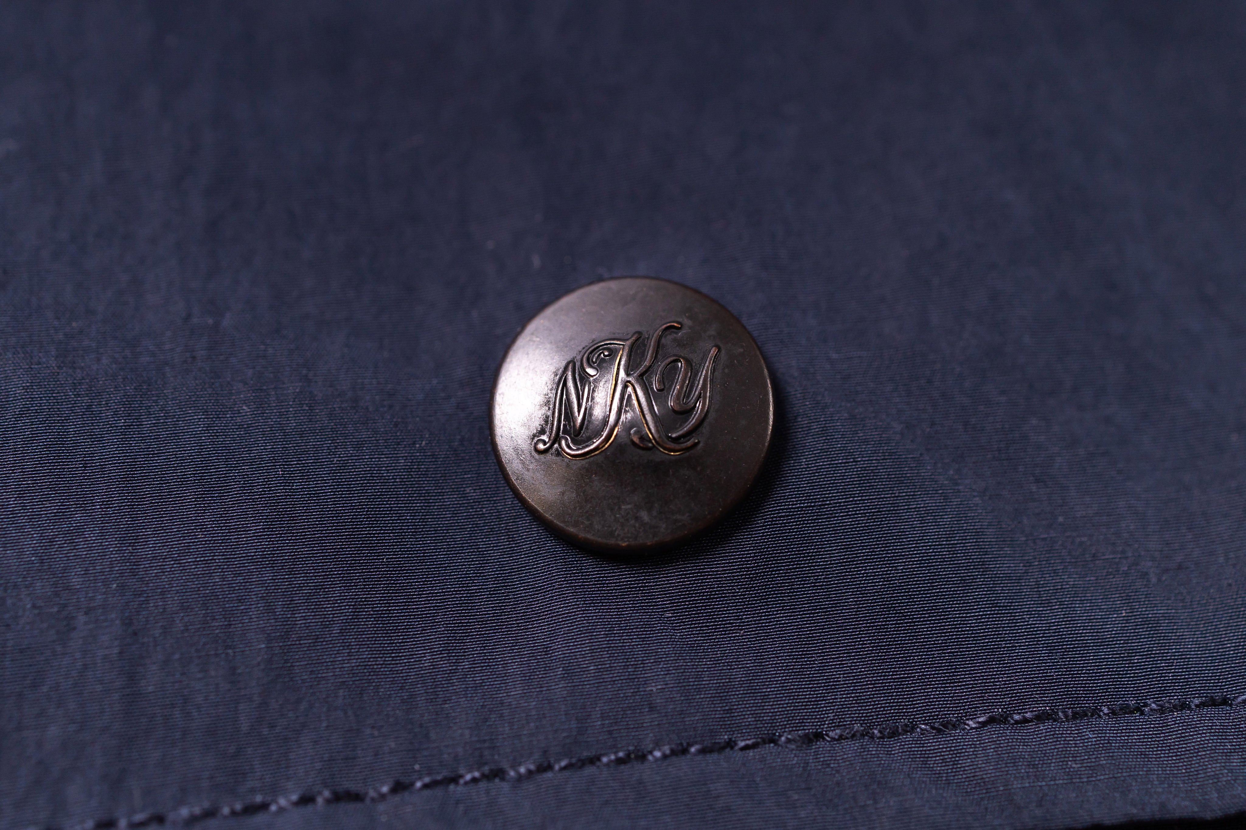 Close-up of a button with 'NKY' on a dark fabric background