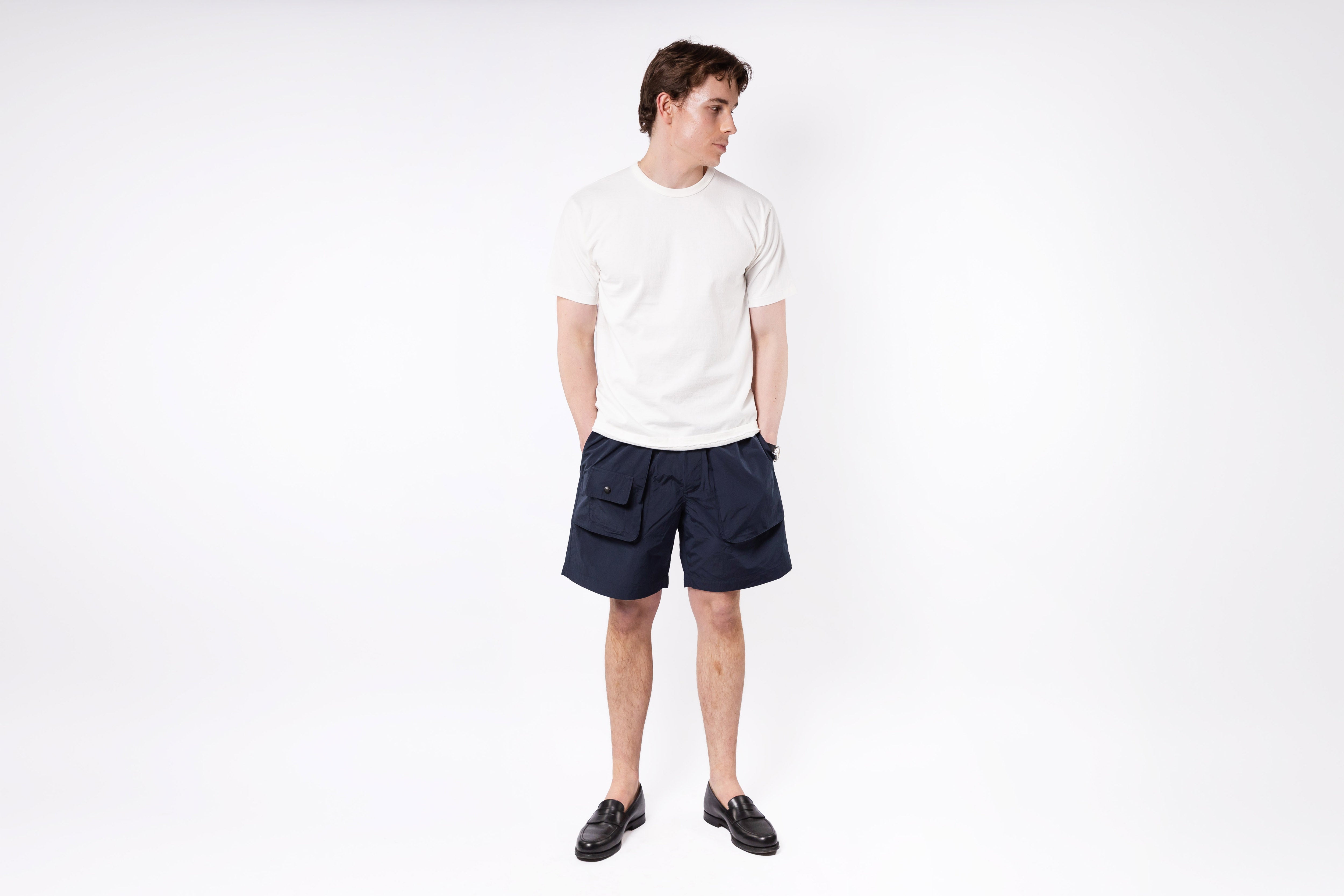 Person wearing a white t-shirt and navy shorts on a white background
