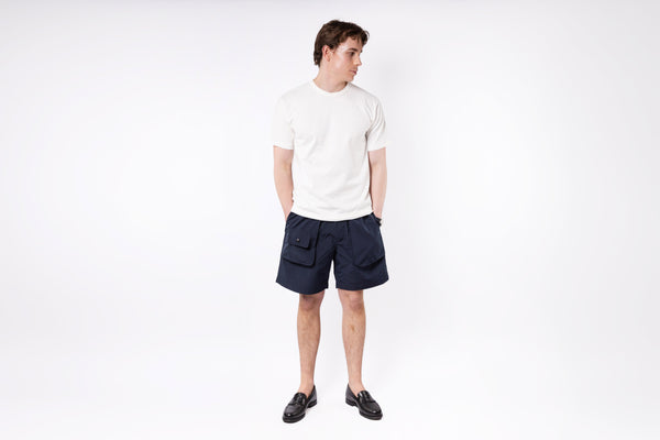 Person wearing a white t-shirt and navy shorts on a white background
