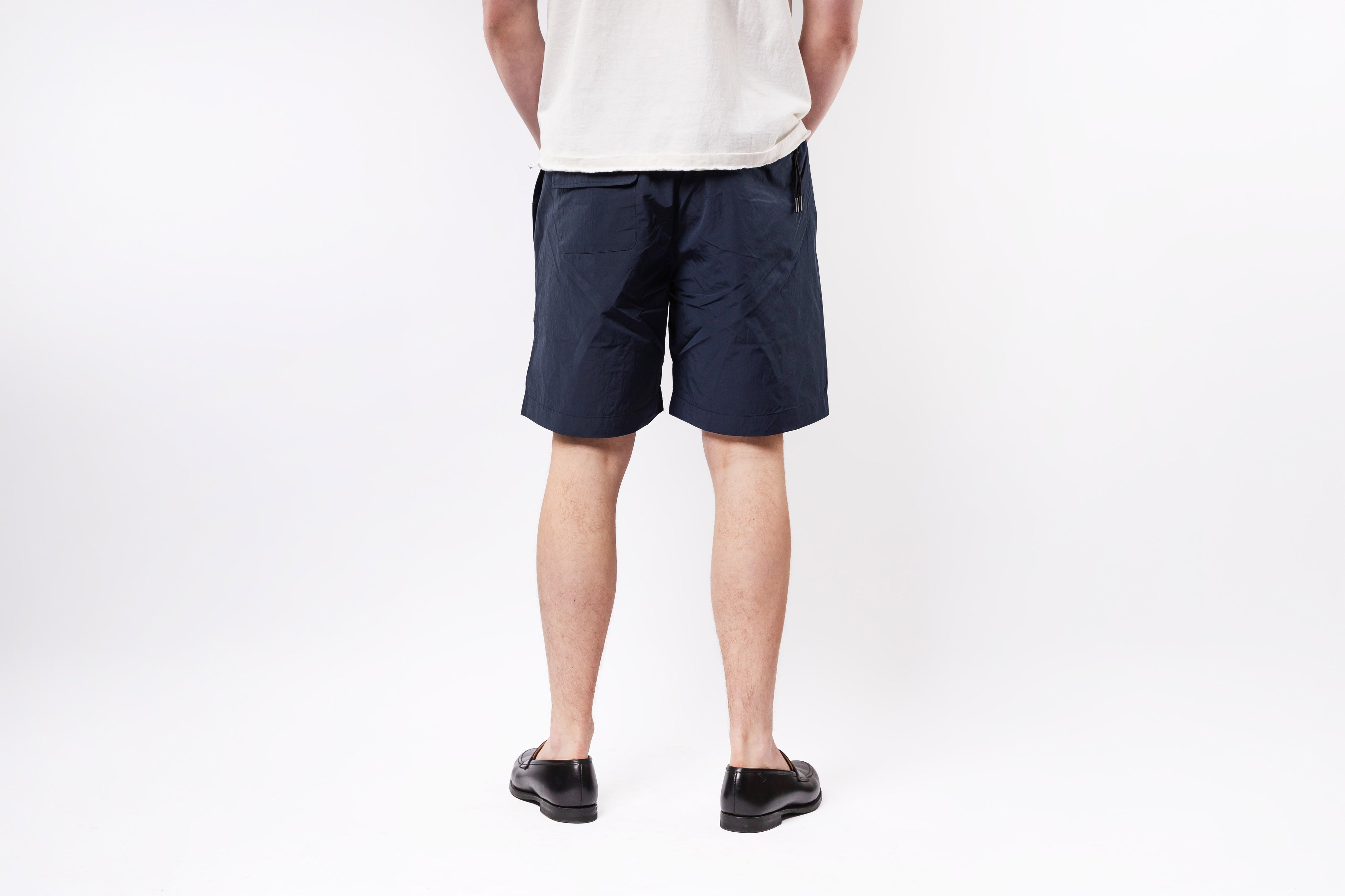 Person wearing navy shorts on a white background