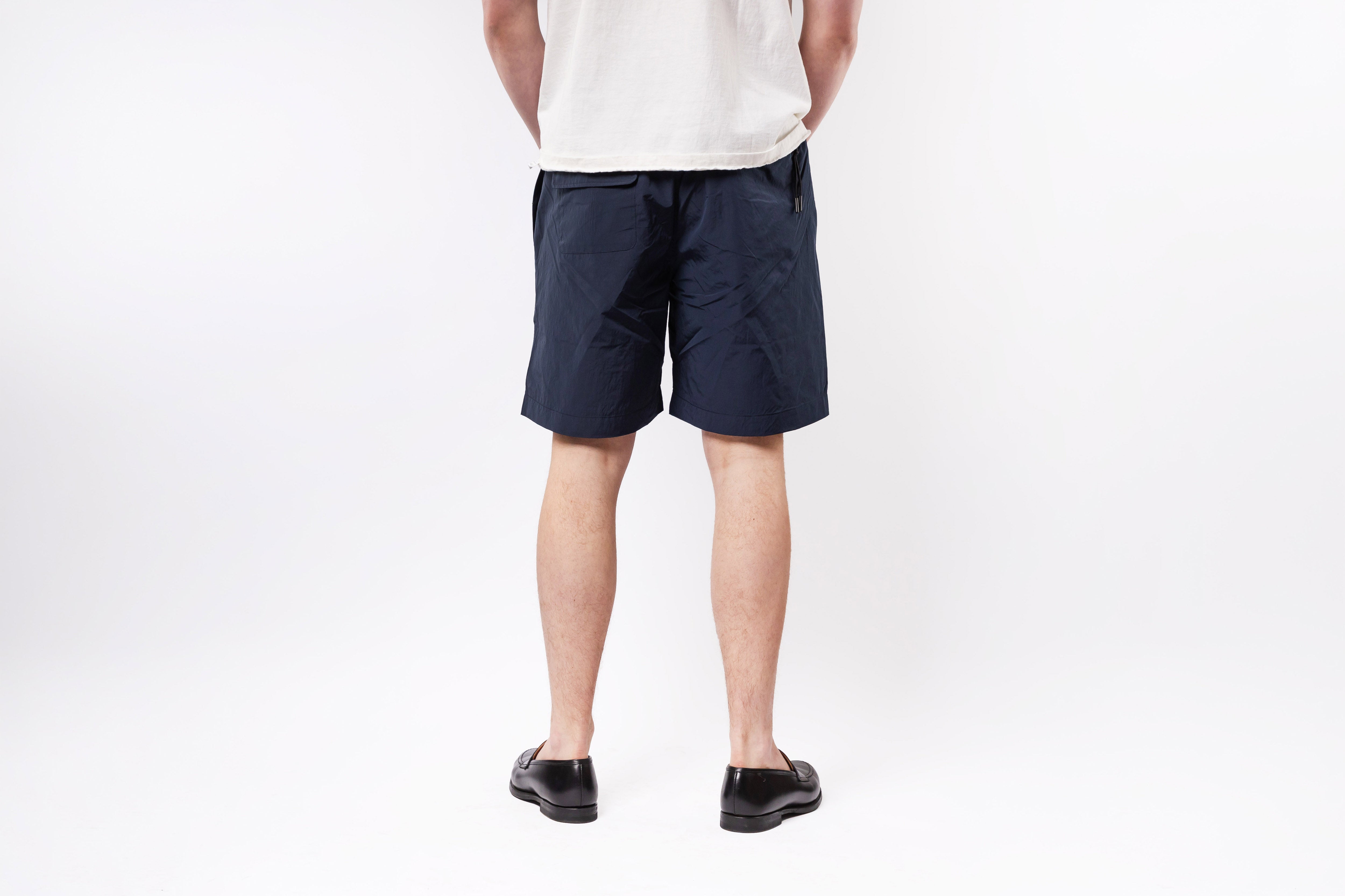 Person wearing navy shorts on a white background