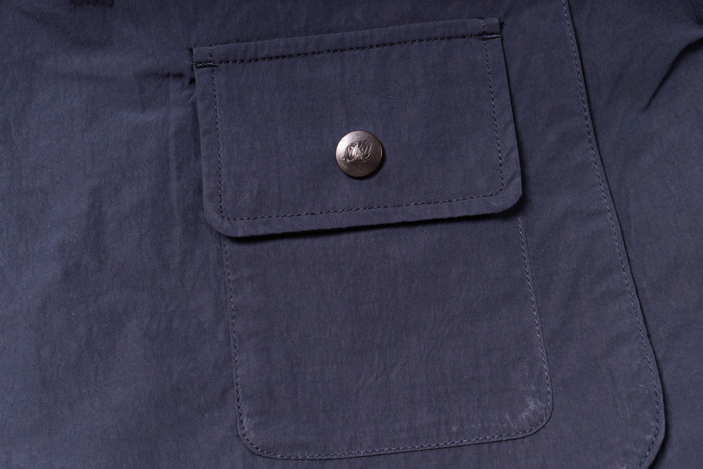Close-up of a navy blue jacket pocket with a button on a dark background