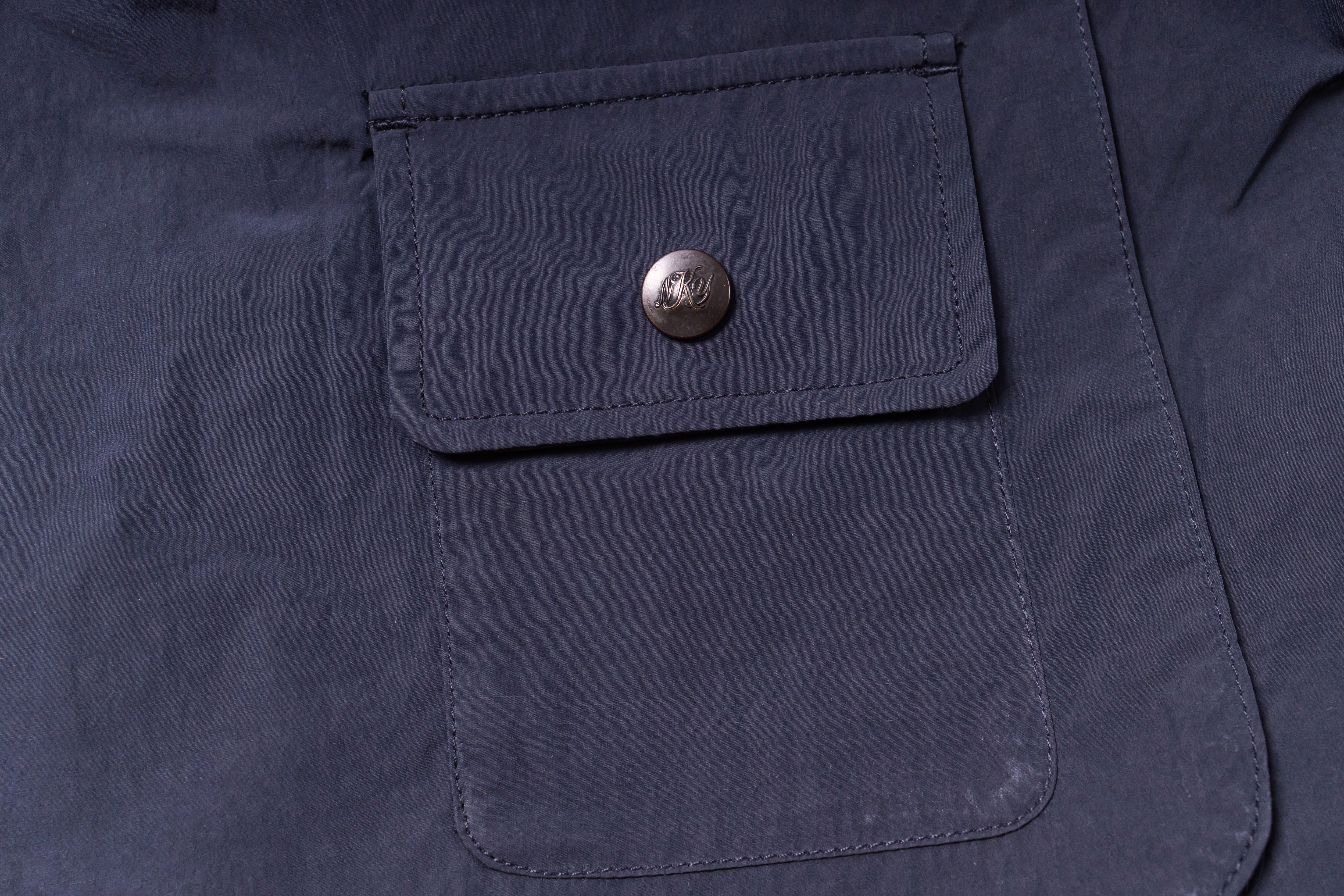 Close-up of a navy blue jacket pocket with a button on a dark background