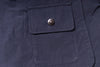 Close-up of a navy blue jacket pocket with a button on a dark background