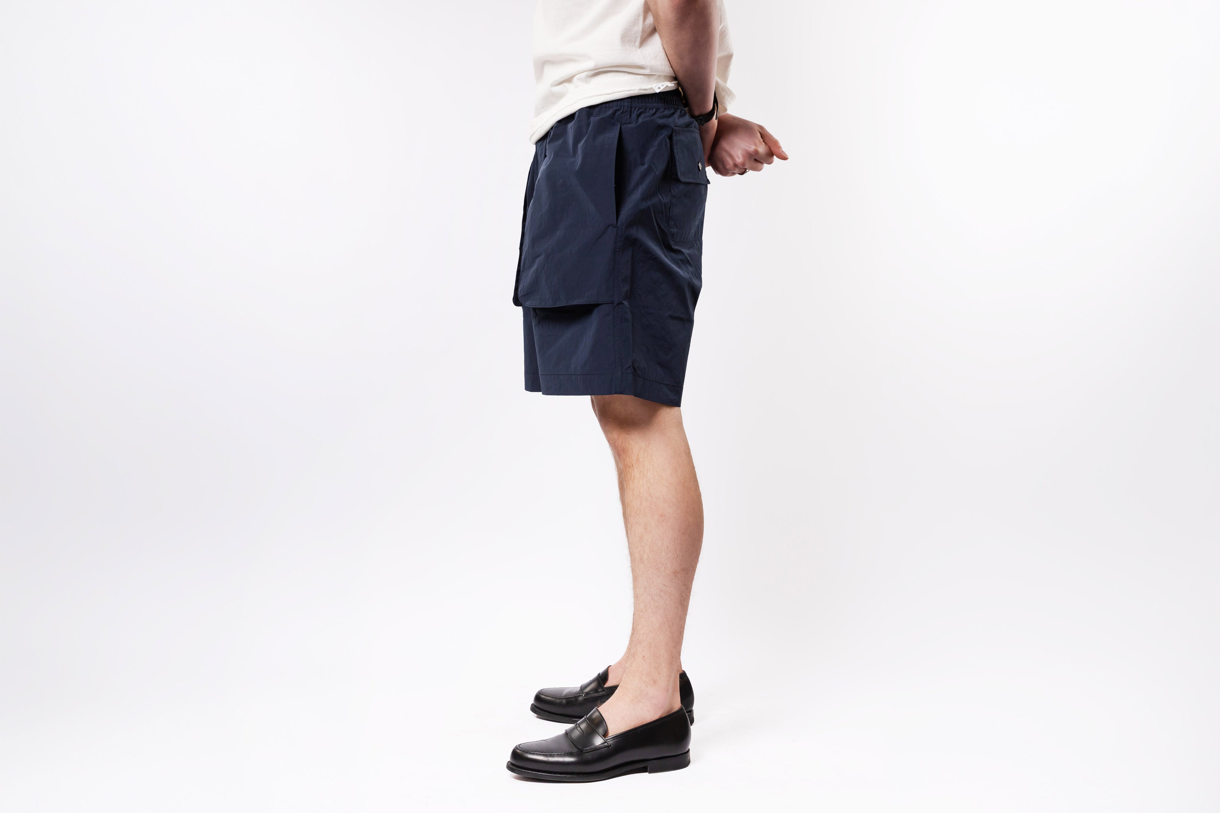 Person wearing navy cargo shorts on a white background
