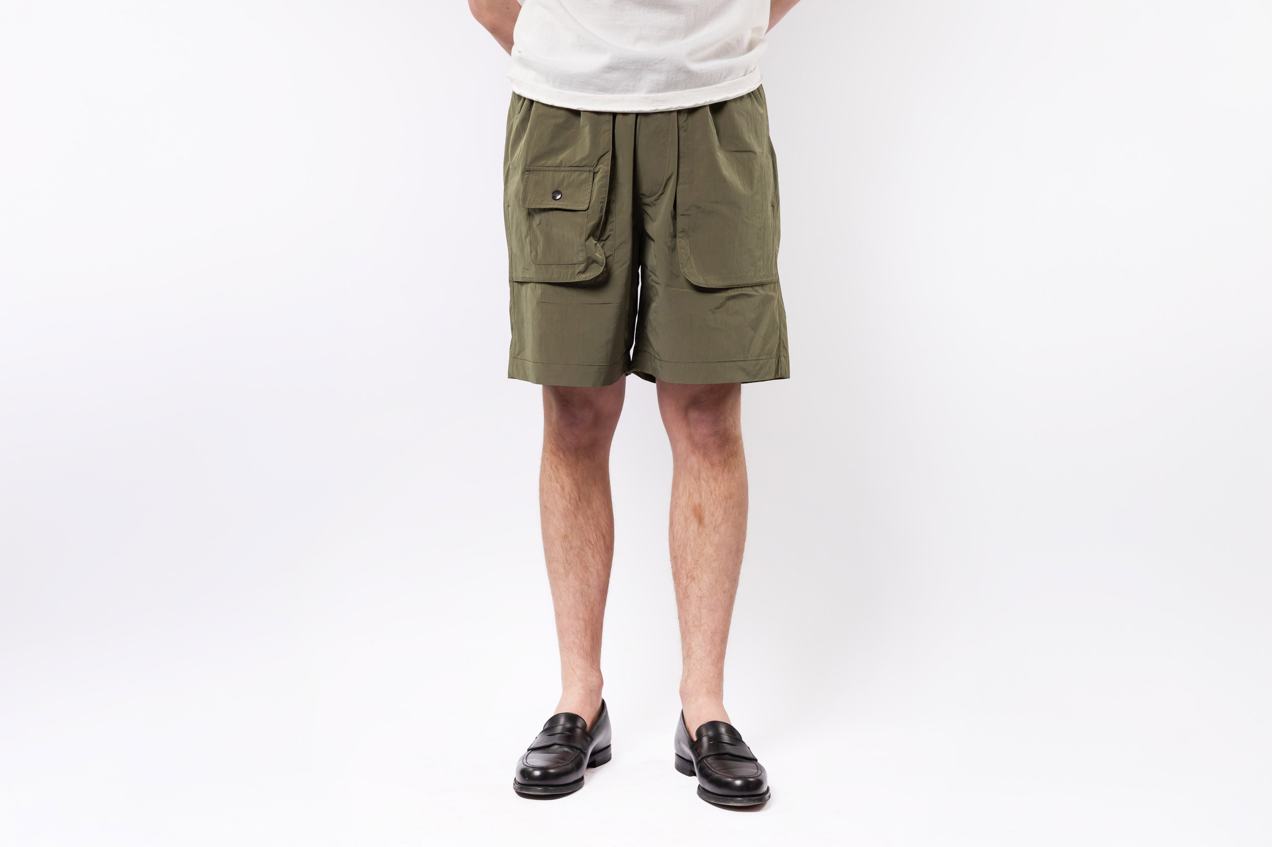 Person wearing olive green cargo shorts on a white background
