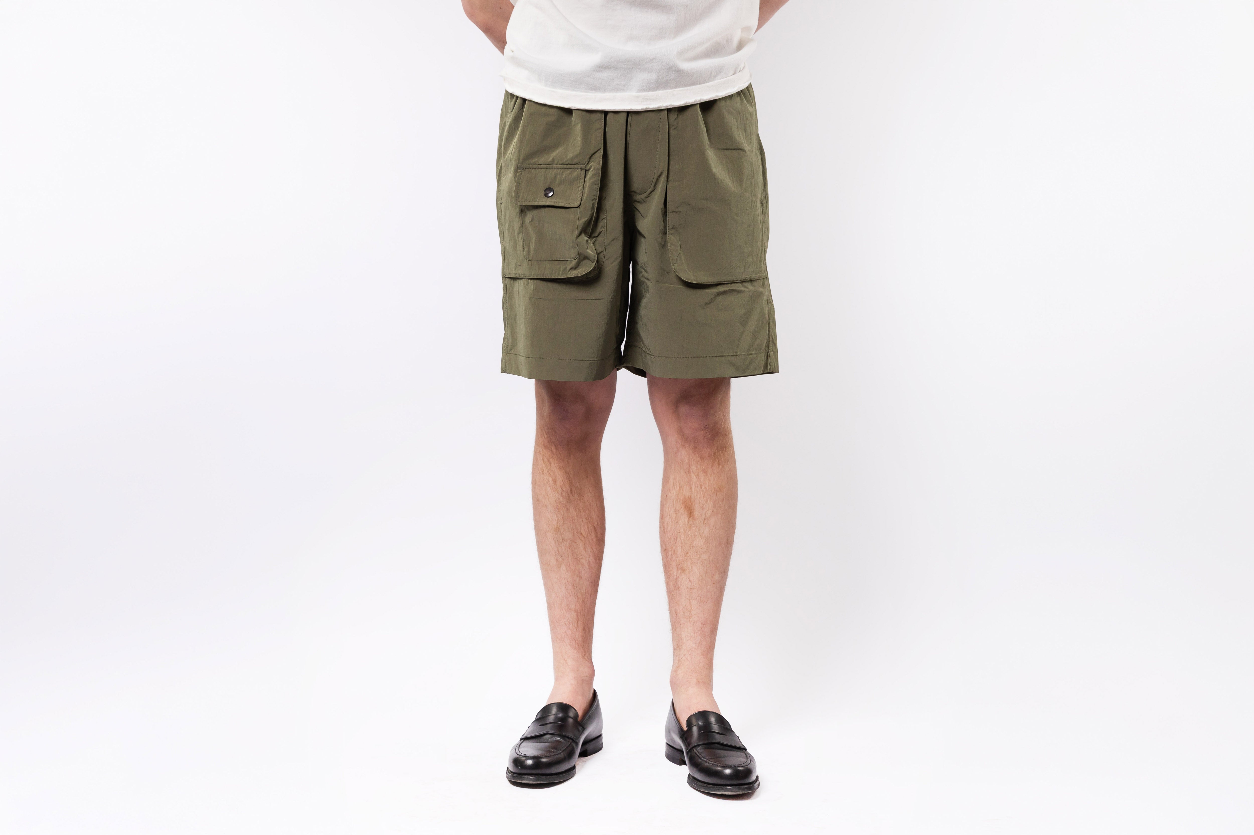 Person wearing olive green cargo shorts on a white background