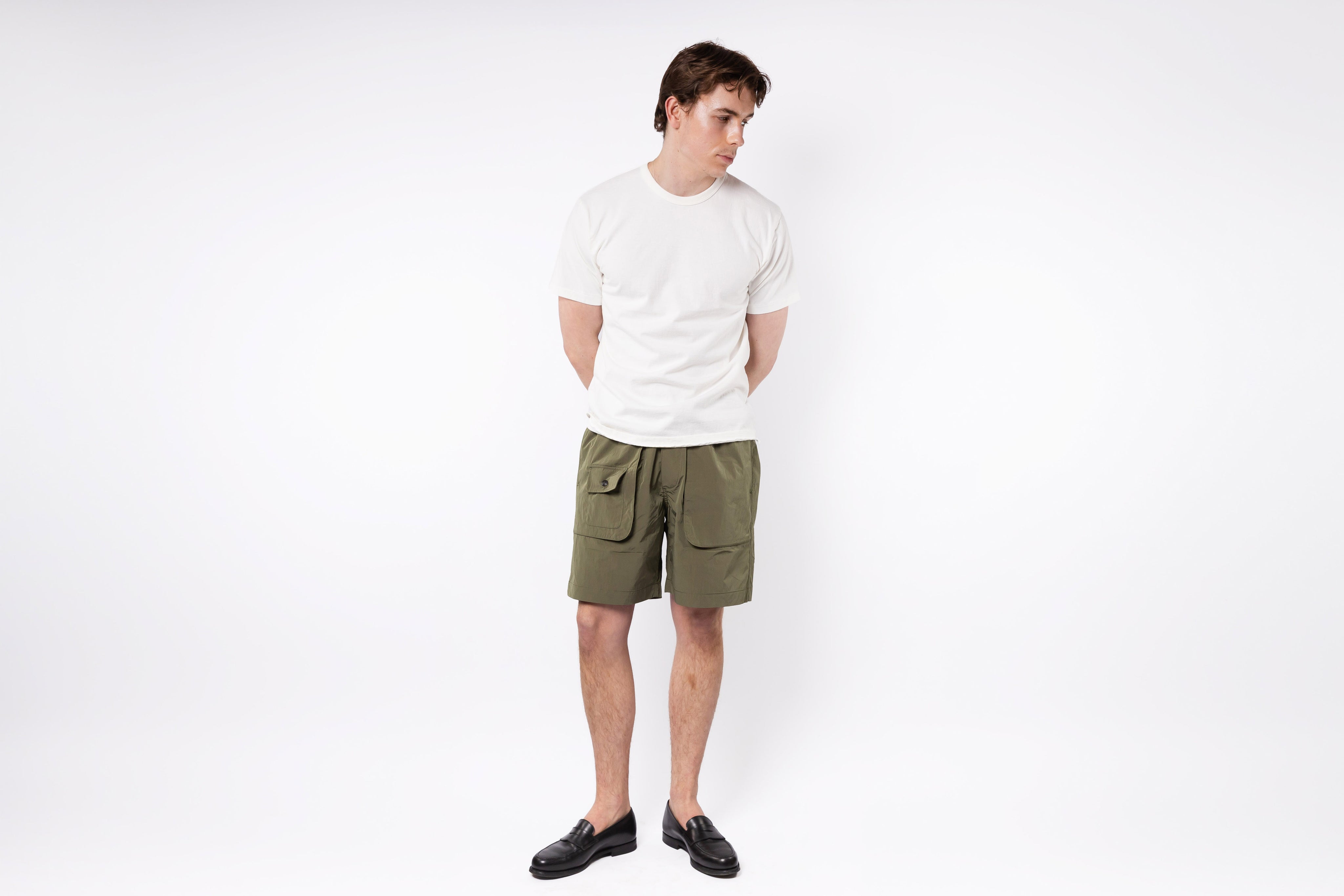Person wearing a white t-shirt and green shorts on a white background