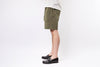 Person wearing olive green shorts and black shoes on a white background