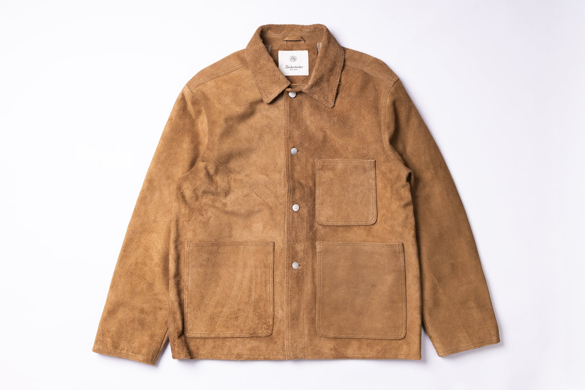 A tan suede utility jacket with a pointed collar, snap-button front, and four front pockets, laid flat against a white background.