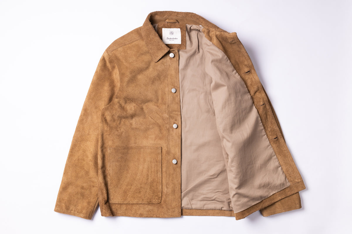 A tan suede jacket with a beige lining, laid flat against a white background.