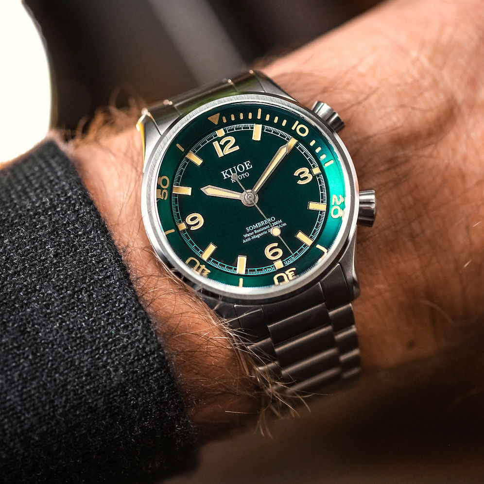 A close-up shot of a wrist wearing a Kliever Schaffner automatic watch with a green dial and a stainless steel link bracelet.