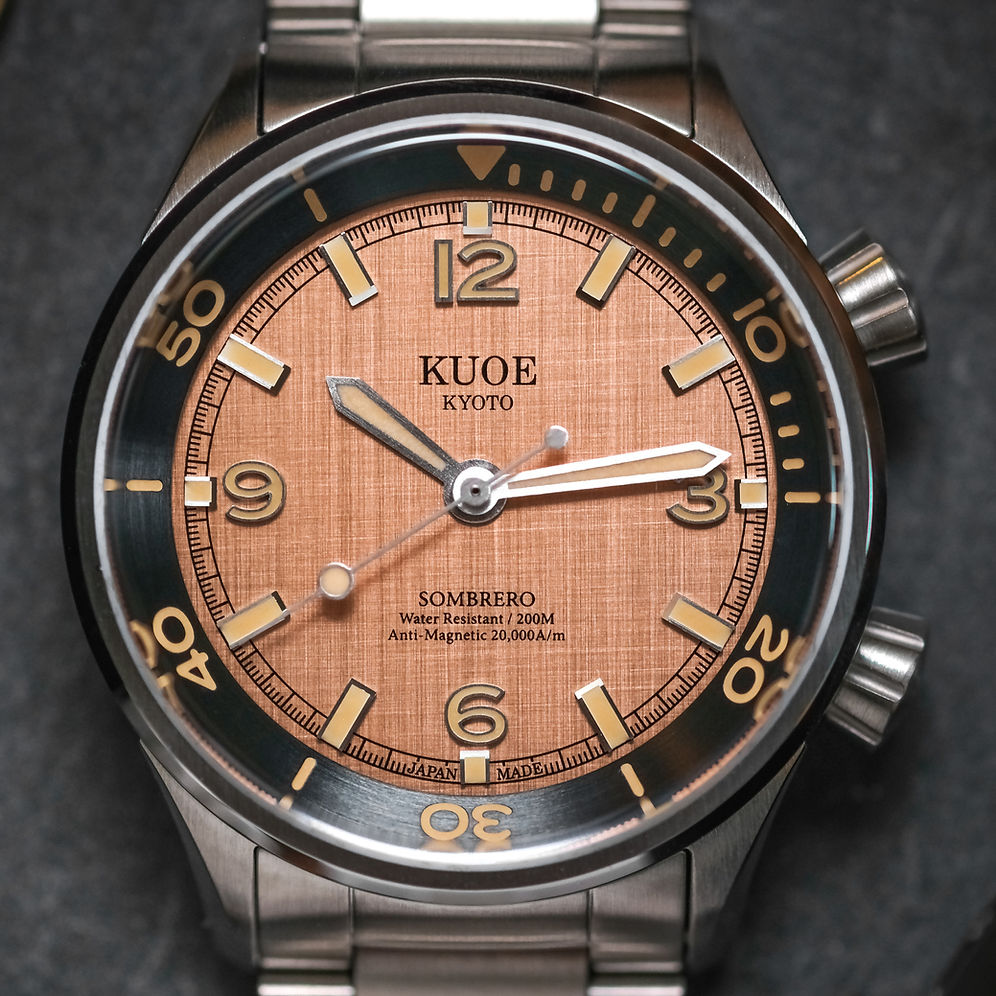Close-up of a Kuoe Kyoto Sombrero wristwatch with a brushed copper dial, black bezel, and stainless steel bracelet.