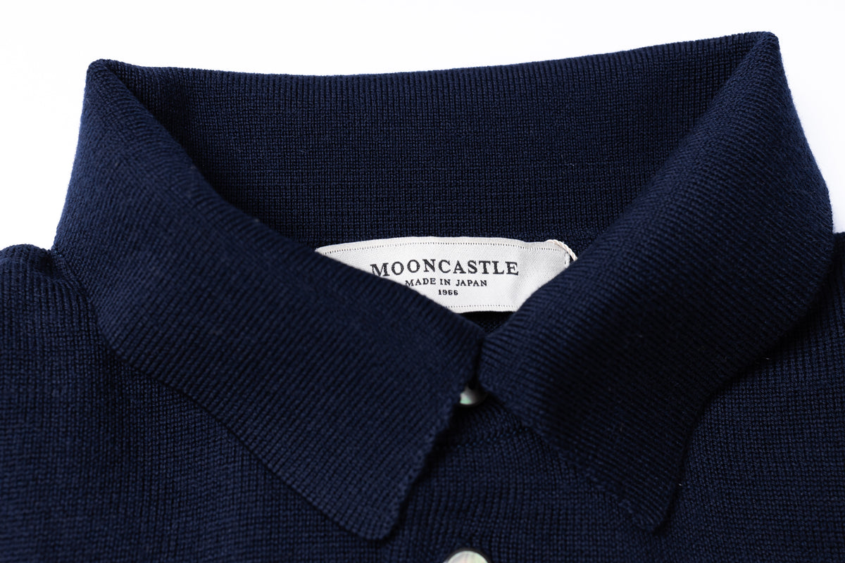 Close-up of a dark navy knit polo shirt collar with a white inner neck label reading MOONCASTLE MADE IN JAPAN 1966, on a white background.