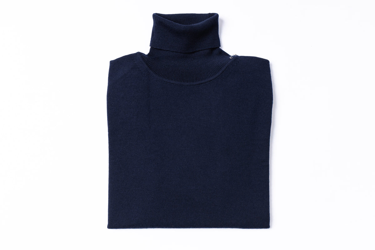 A folded navy blue knit turtleneck sweater on a solid white background.