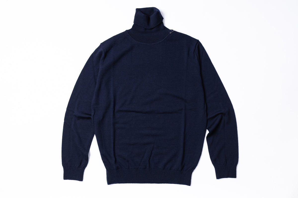 A dark navy blue turtleneck sweater laid flat against a clean white background.