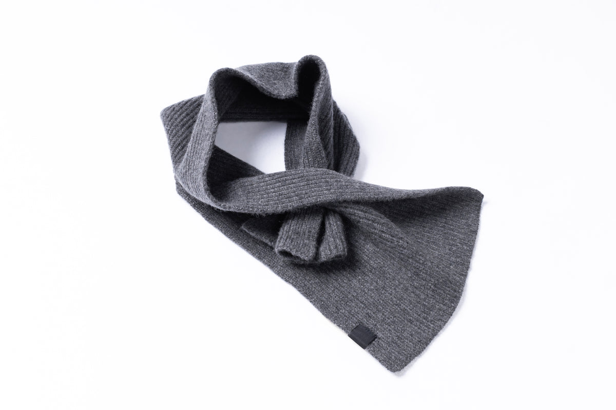 A dark gray ribbed knit scarf tied in a loose knot, displayed on a clean white background.