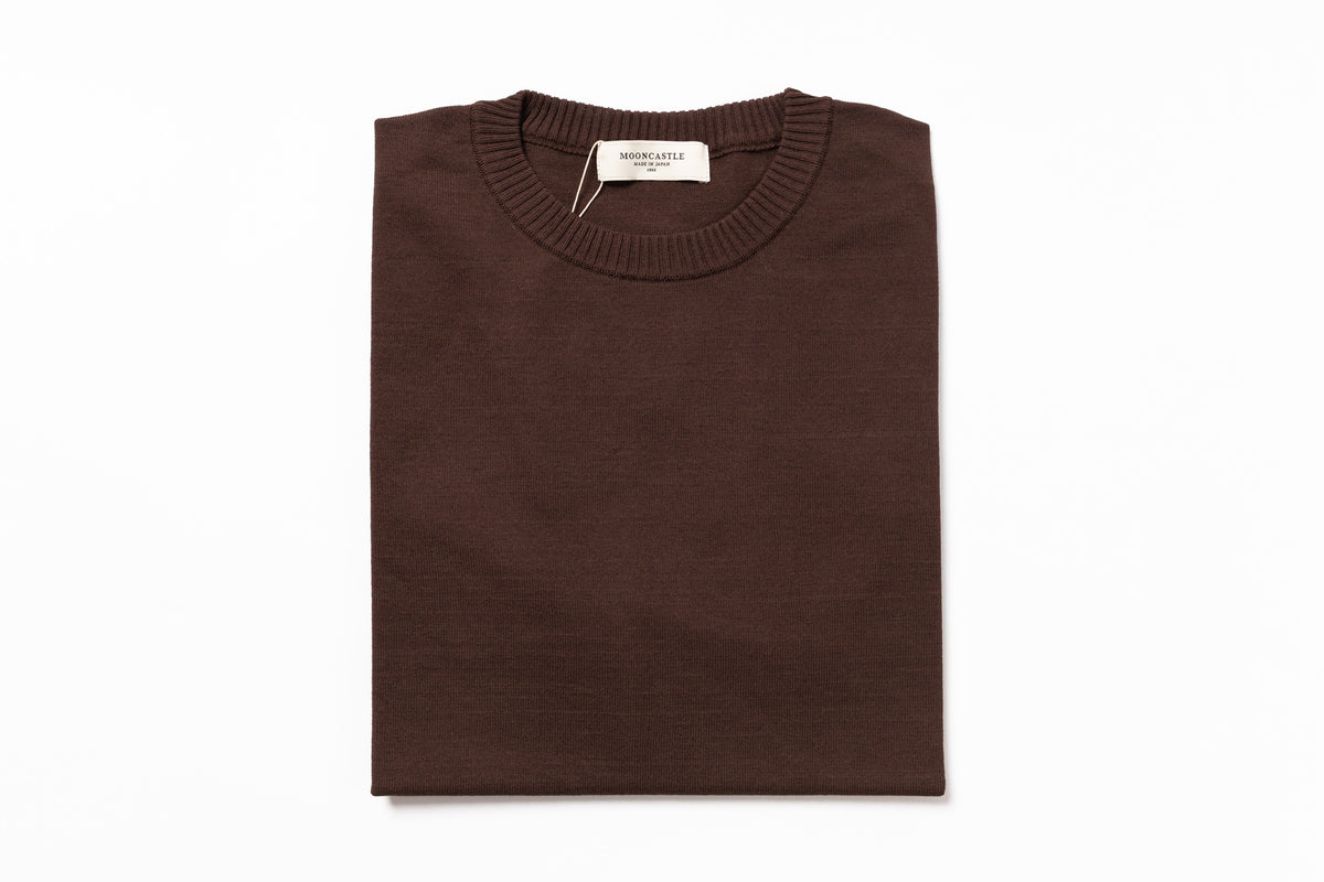 Folded brown sweater with a brand tag on a white background