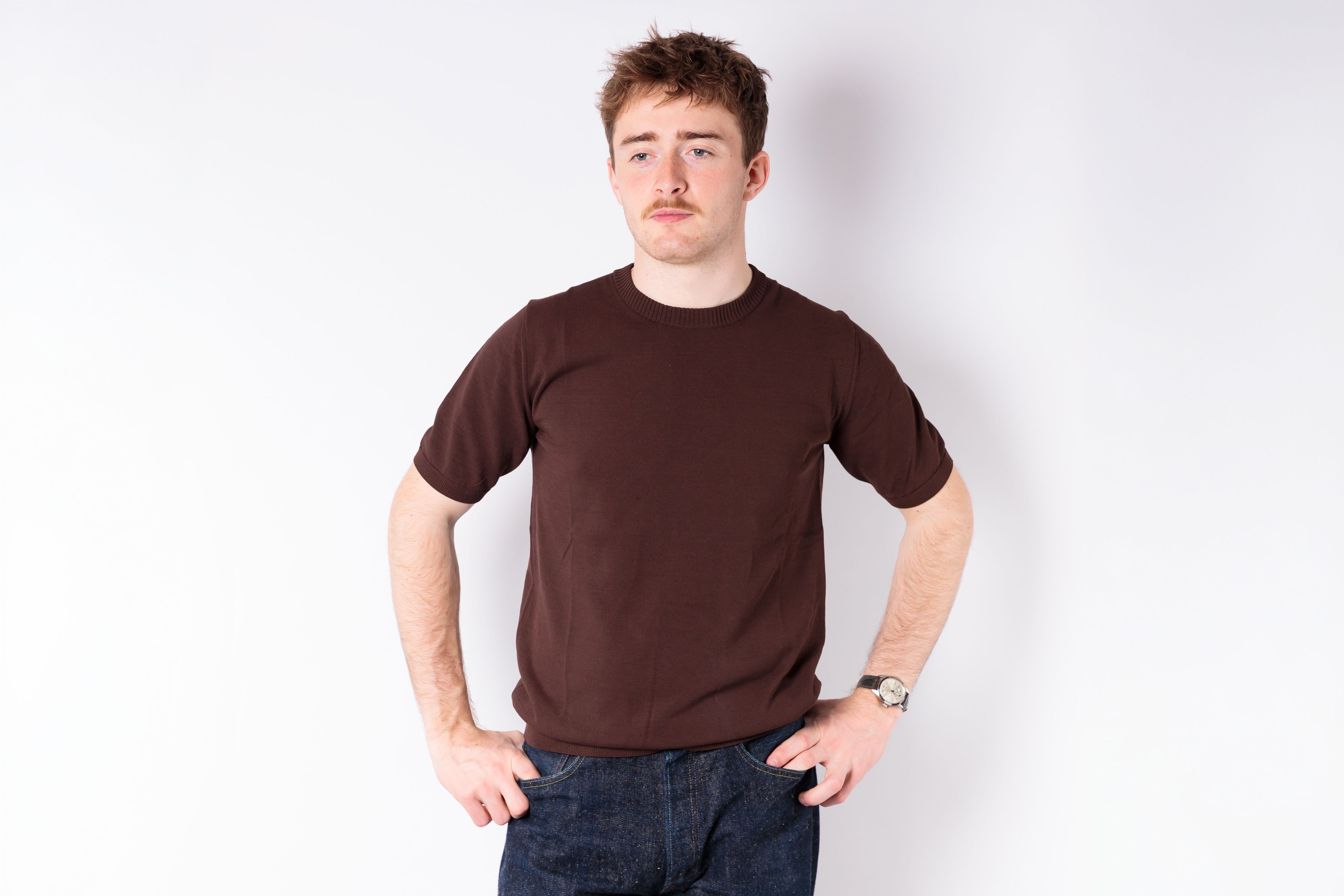 Person wearing a brown t-shirt against a white background