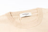 Beige sweater with a visible brand label on a white background