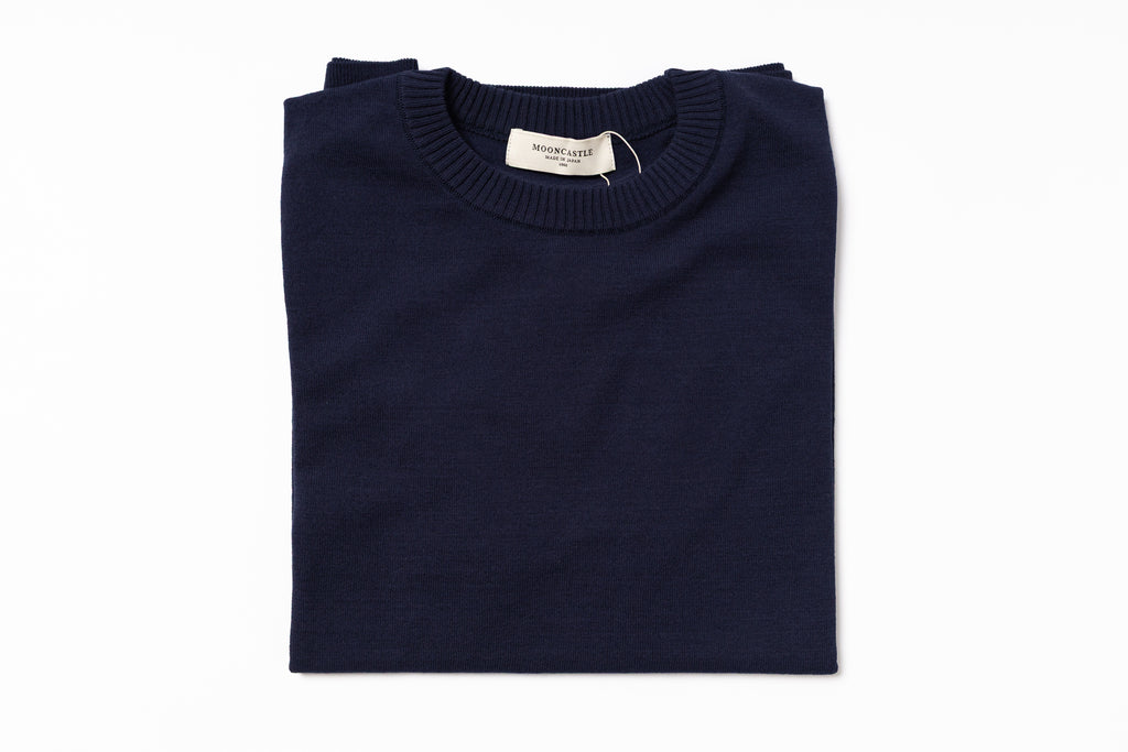 Folded navy blue sweater with a label on a white background