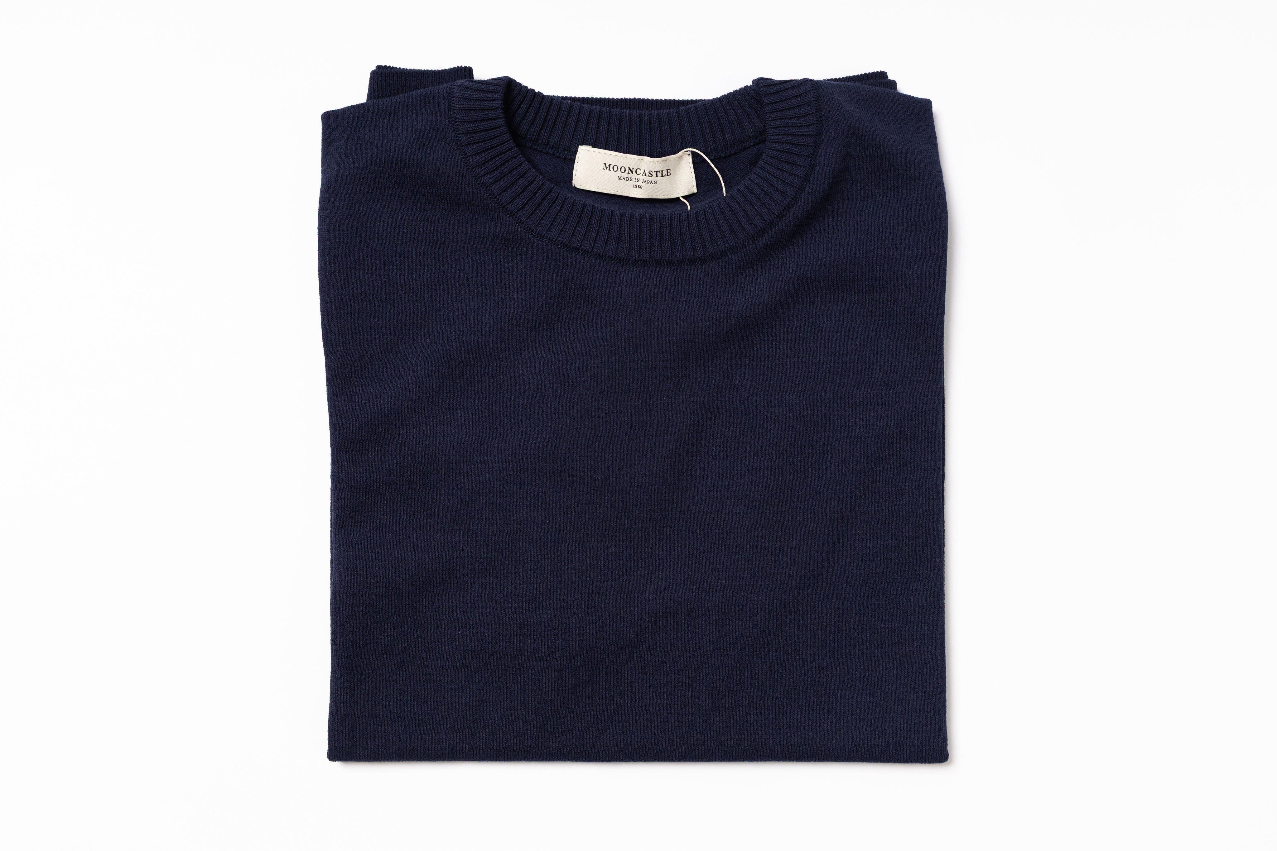 Folded navy blue sweater with a label on a white background
