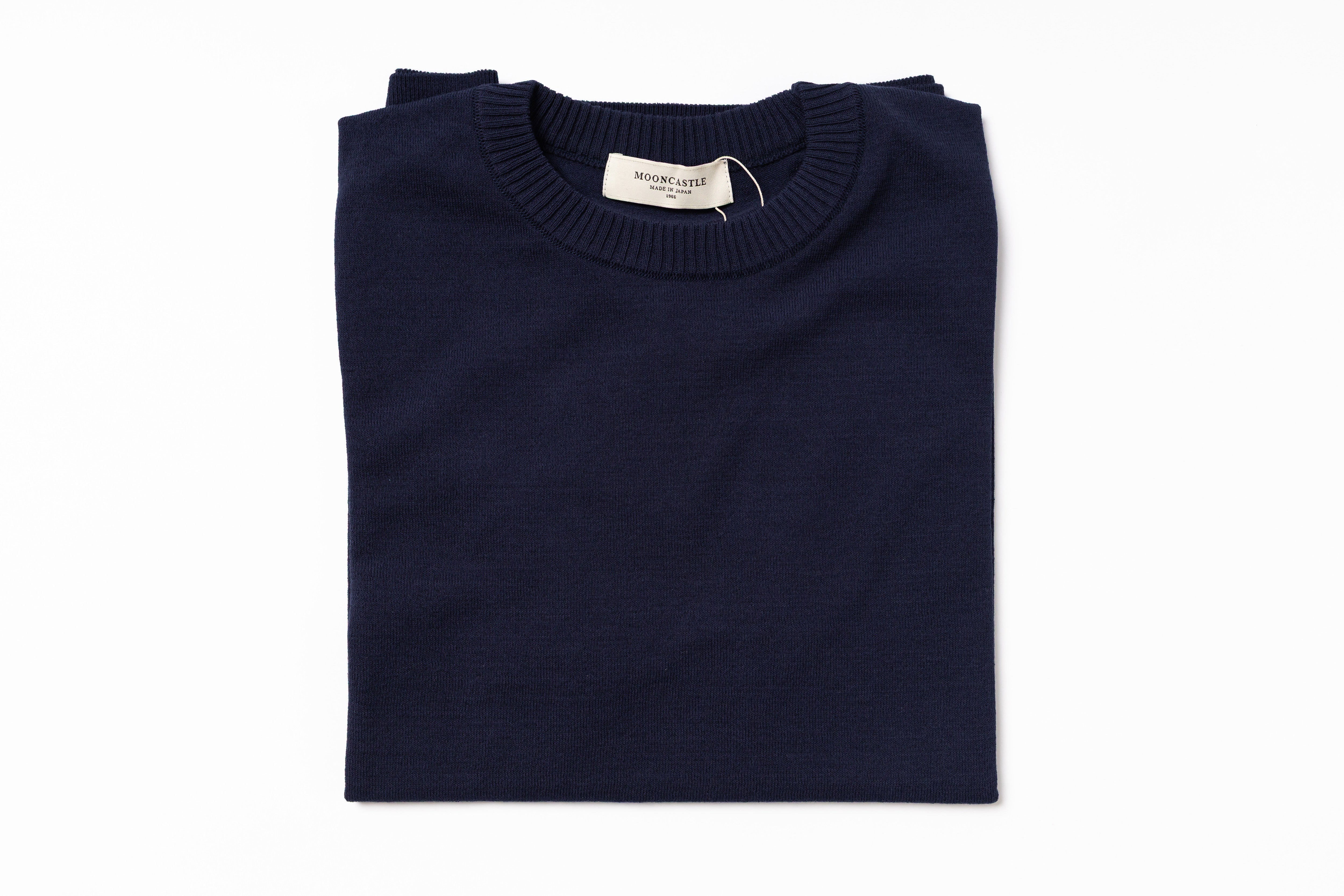 Folded navy blue sweater with a label on a white background