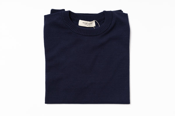 Folded navy blue sweater with a label on a white background