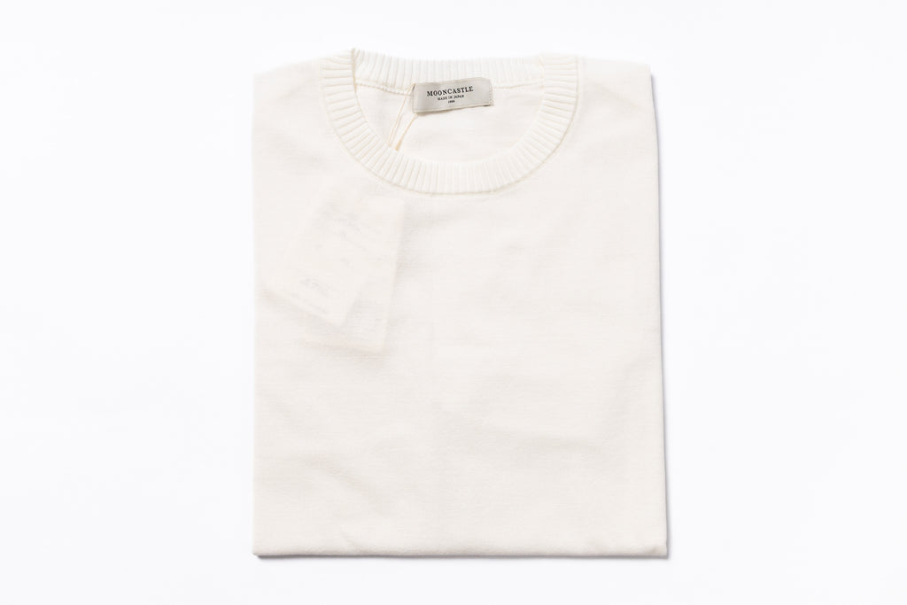 Folded white sweater with a brand label on a white background