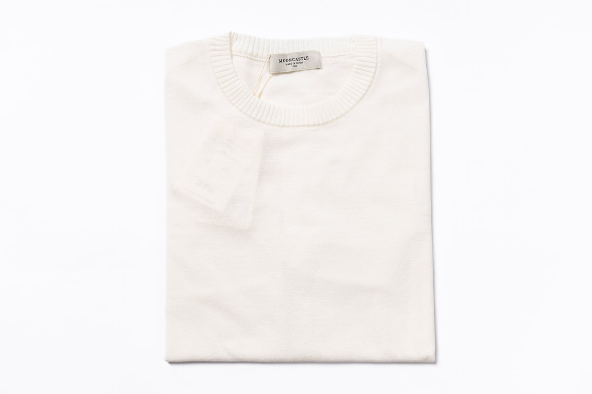 Folded white sweater with a brand label on a white background