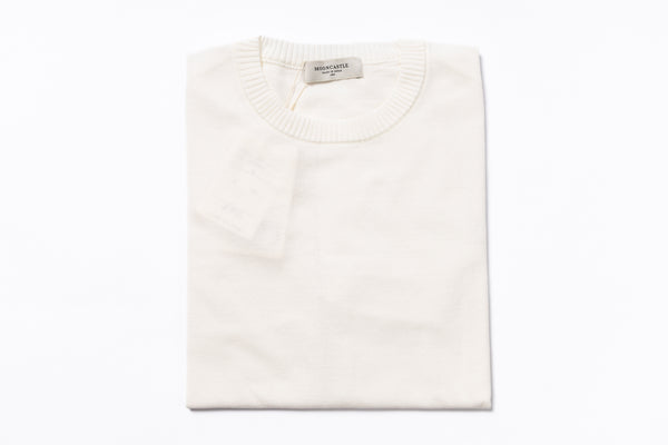 Folded white sweater with a brand label on a white background