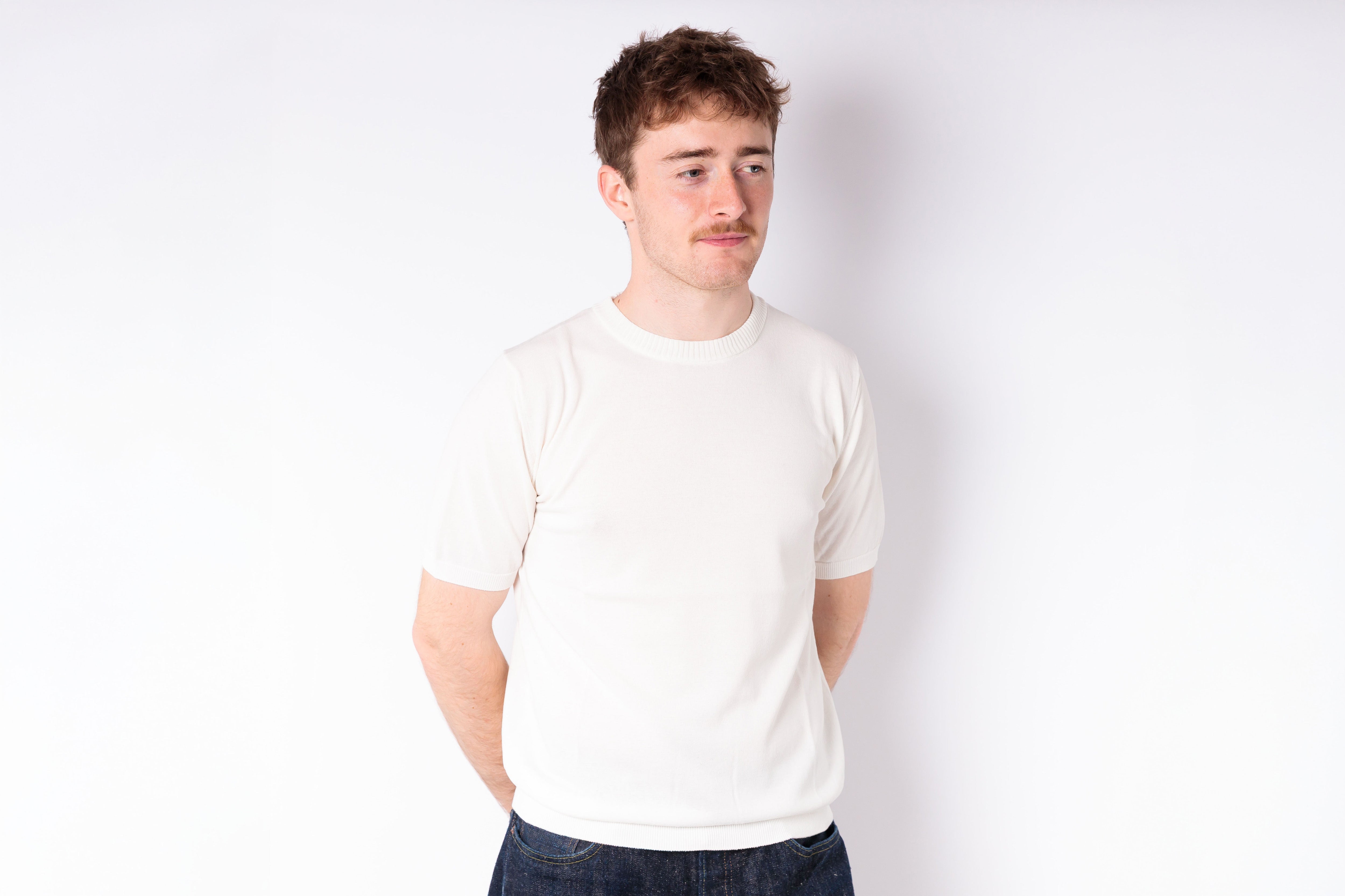 Man wearing a plain white t-shirt against a white background