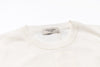 White sweater with a visible brand tag on a white background