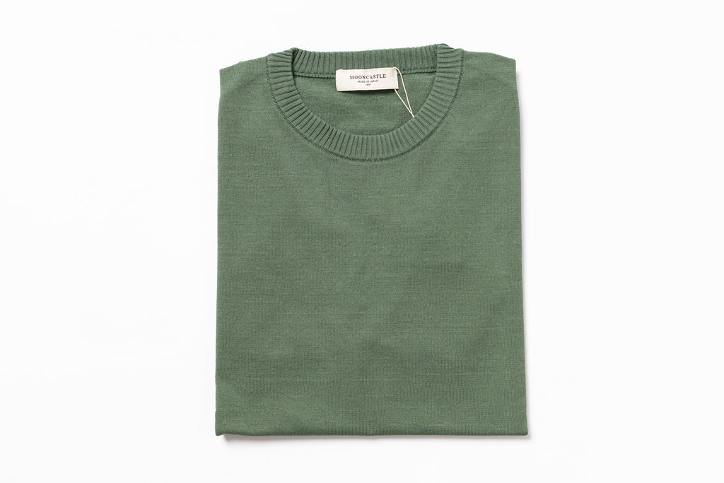 Folded green sweater on a white background