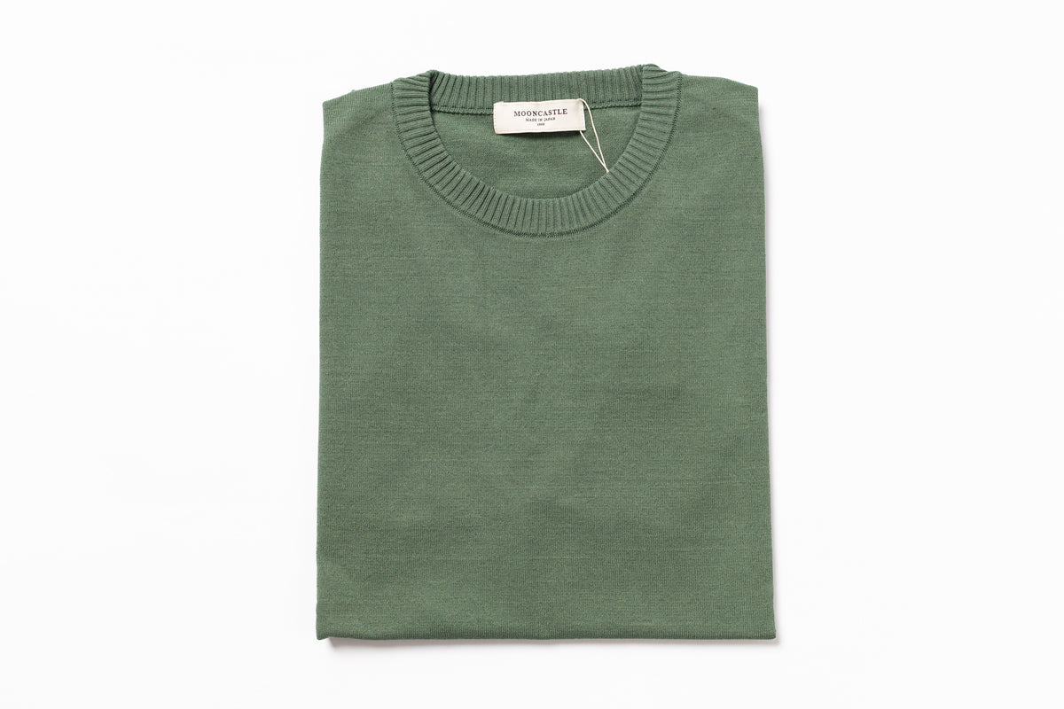 Folded green sweater on a white background