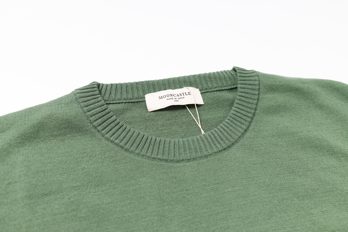 Green sweater with a brand tag on a white background