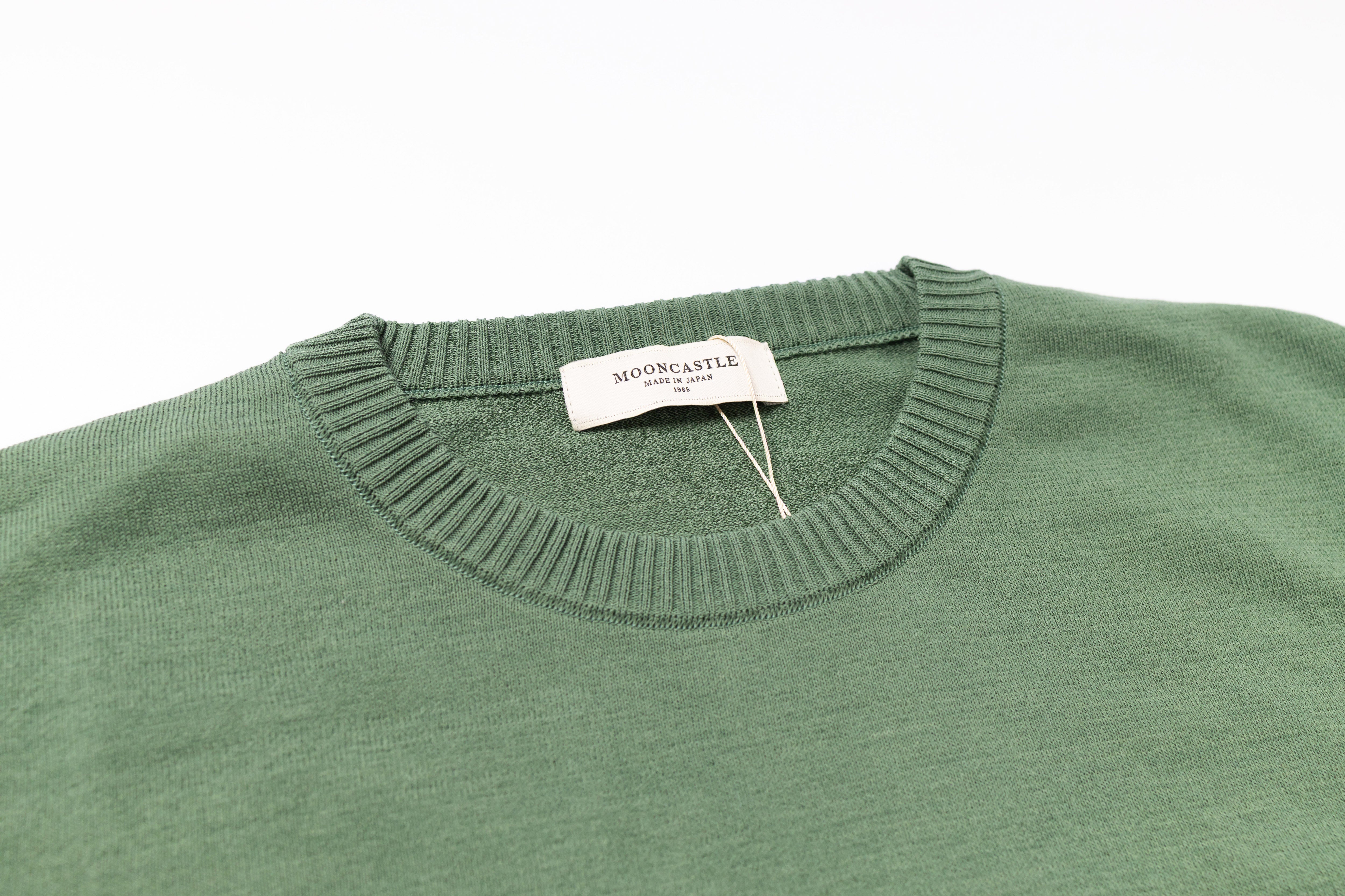 Green sweater with a brand tag on a white background
