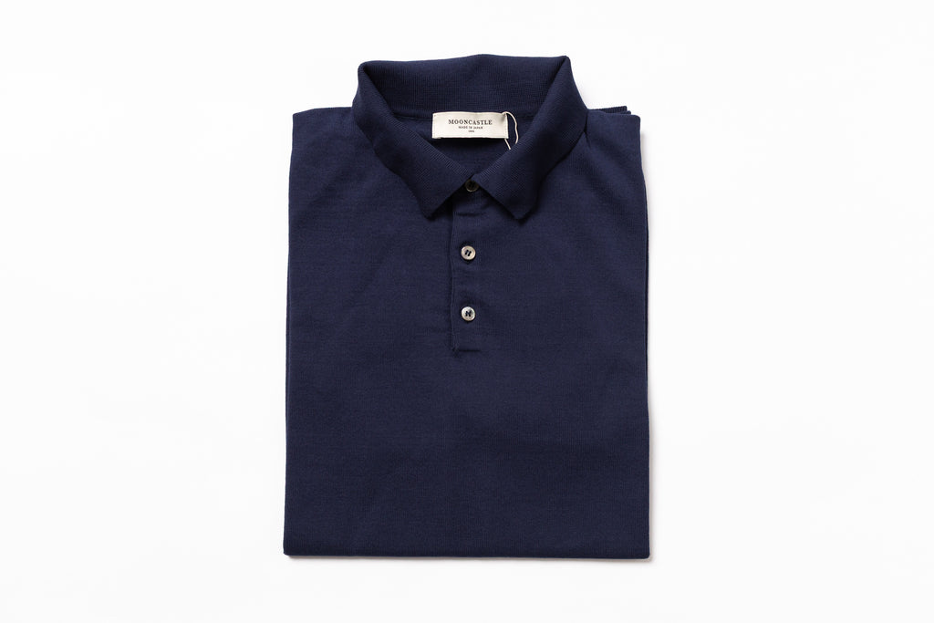 Folded navy blue polo shirt with a brand label on a white background